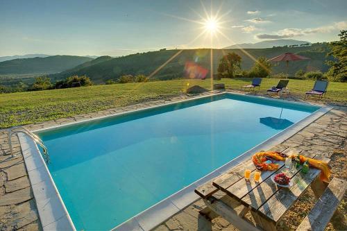 Una gran piscina azul con una mesa y sillas. en Villa Torre Luna by Mmega, en Misciano