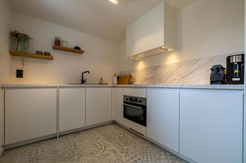 a white kitchen with white cabinets and a stove at Guesthouse Westende in Middelkerke