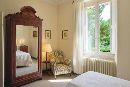 a bedroom with a mirror and a chair and a window at Villa delle Marche by BarbarHouse in Rosciano