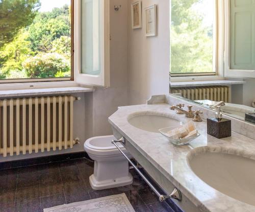 a bathroom with two sinks and a toilet and windows at Villa delle Marche by BarbarHouse in Rosciano