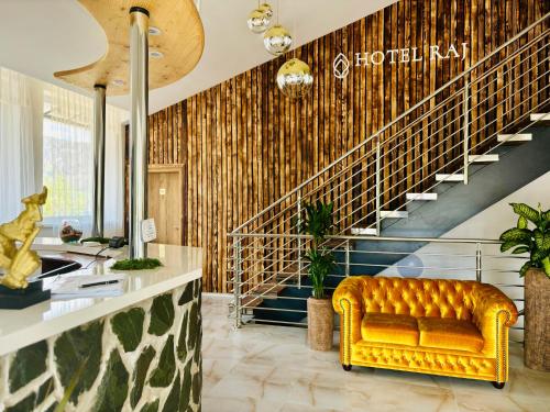 a lobby with a yellow couch in front of a staircase at Hotel Raj in Dedinky