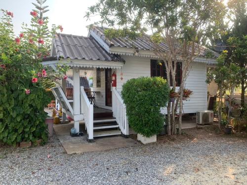 a small white house with a porch and stairs at นอนนี่แอทเขาค้อ in Khao Kho