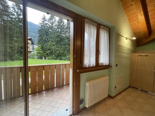 a room with a balcony with a large window at Residence Valentino in Pinzolo