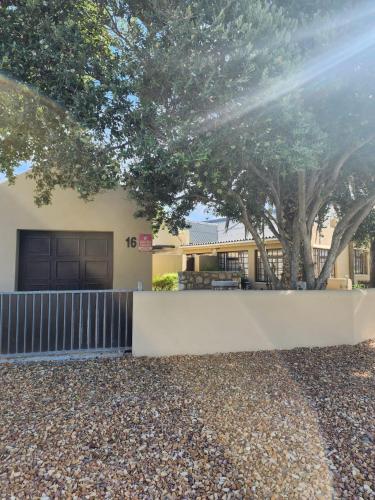 a house with a fence and trees in front of it at 16 on Main Arniston PET-FRIENDLY in Arniston