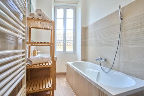 uma casa de banho com uma banheira, um lavatório e um espelho. em Les Appartements de la Cadène em Saint-Émilion