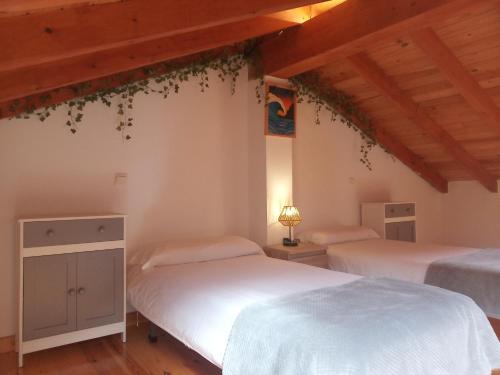two beds in a room with wooden ceilings at Casa Rural Villapresente in Reocín