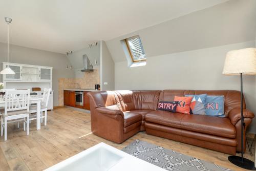a living room with a brown leather couch and a kitchen at Rent like home - Sienkiewicza in Zakopane