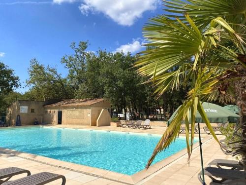 une grande piscine bordée d'un palmier dans l'établissement Camping maeva Escapades Le Domaine des Chênes Blancs, à Croagnes