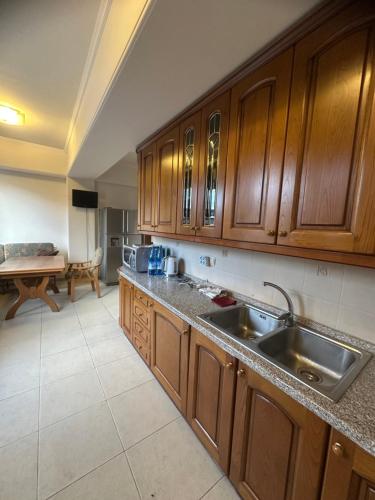 a kitchen with wooden cabinets and a stainless steel sink at Roma Apartament in Yerevan