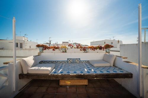 balcone con letto e sedie sul tetto di Casa Hibiscus a Vejer de la Frontera