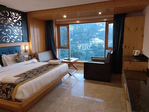een slaapkamer met een groot bed en een groot raam bij Hotel Queen Plaza A Unit of JARA Hotels & Resorts in Mussoorie