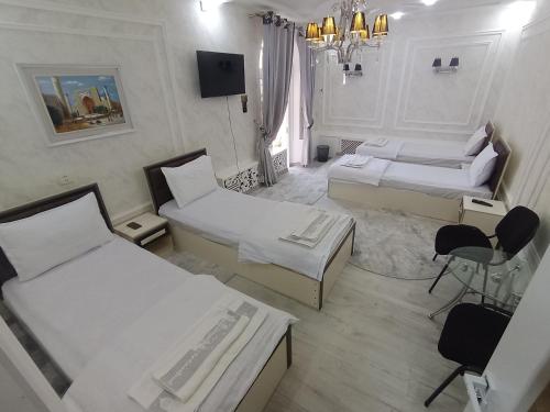 una stanza con due letti, un tavolo e delle sedie di Abubakir Guests House a Samarkand