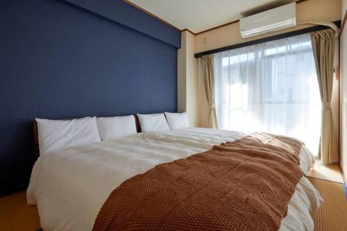 a bedroom with a bed with a blue wall and a window at 2BR 4 Beds 6 min walk to Sta. Katsushika Hokusai 17 min walk JR Sta. in Nikko