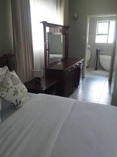 a bedroom with a bed and a television and a bathroom at Beautiful No Fuss Serene 3 Bed House in Bulawayo in Bulawayo
