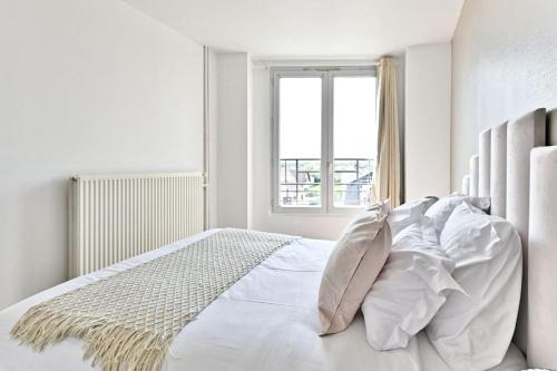 um quarto branco com uma cama com almofadas e uma janela em Appartement moderne et spacieux 2 chambres - Gagny em Gagny