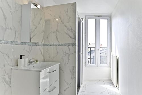 une salle de bain blanche avec un lavabo et une fenêtre dans l'établissement Appartement moderne et spacieux 2 chambres - Gagny, à Gagny