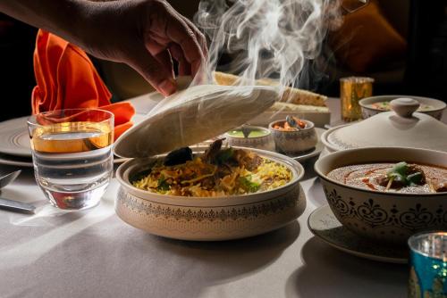 a person is preparing a bowl of food on a table at Al Messila, A Luxury Collection Resort & Spa, Doha in Doha