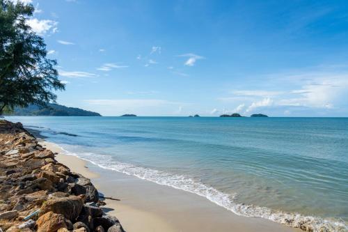 a beach with rocks and the ocean on a sunny day at Koh Chang Longstay Resort in Ko Chang