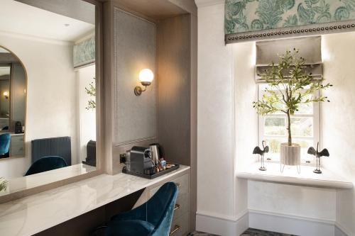 Brig o' Doon House Hotel في آير: غرفة في الفندق مع مرآة وكرسي أزرق
