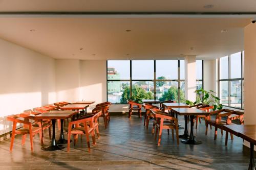 un comedor con mesas, sillas y ventanas en LuckyStar Hotel en Pleiku
