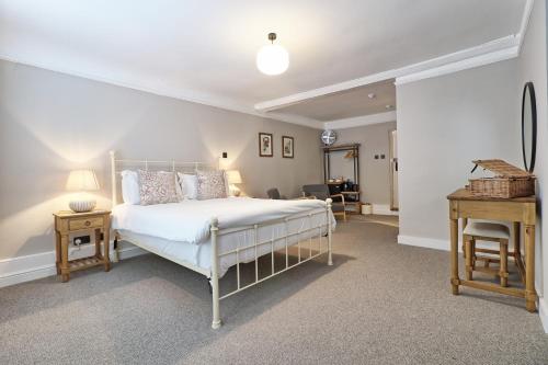 a bedroom with a white bed and a desk at Ranfield's Brasserie Hotel Rooms in Coggeshall