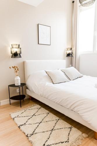 - un lit blanc dans une chambre blanche avec un tapis dans l'établissement Le Soft - Beau logement - Centre - Gare - Tram - Superbe vue Sarthe, au Mans