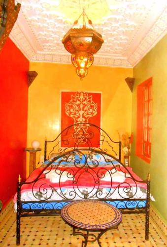 a bedroom with a bed and a table and a chandelier at Riad Jennah Rouge in Marrakech