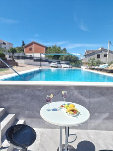 a table with two glasses and a plate of fruit next to a pool at Luxury Apartments Silva with sea view in Trogir
