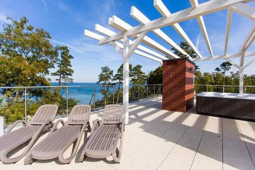 a patio with chairs and a white pergola at Apartament Holiday Crystal in Rewal
