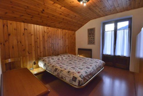 sypialnia z łóżkiem i drewnianą ścianą w obiekcie Casa Faè Dolomiti w Madonna di Campiglio