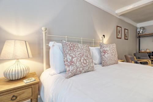 una camera da letto con letto bianco, cuscini e lampada di Ranfield's Brasserie Hotel Rooms a Coggeshall