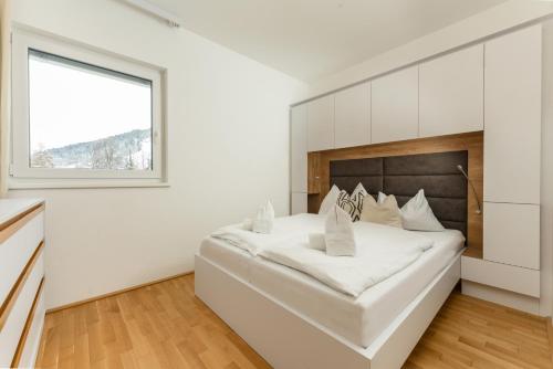 a white bedroom with a large bed and a window at Stadtdomizil Schladming by Schladming-Appartements in Schladming