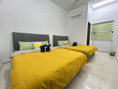 two beds with yellow sheets in a room at D'Teluk Kemang Homestay @ PD in Port Dickson