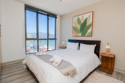a bedroom with a large bed with a large window at 1402 Hibernian Towers Luxury Self Catering Apartment Strand Western Cape South Africa in Cape Town
