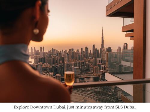 a woman holding a glass of wine looking at the city at SLS Dubai Hotel & Residences in Dubai