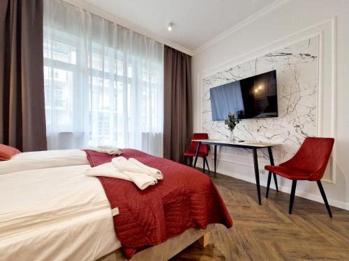 a bedroom with a bed and a table and a tv at Baltic Home in Świnoujście