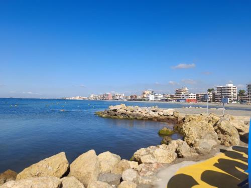 a beach with rocks and a city in the background at Apartamento Caravaca in Santa Pola