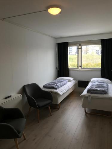 um quarto com duas camas e uma cadeira e uma janela em Volsdalen Camping em Ålesund