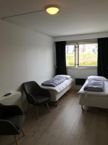 Una habitación con dos camas y una silla y una ventana. en Volsdalen Camping, en Ålesund