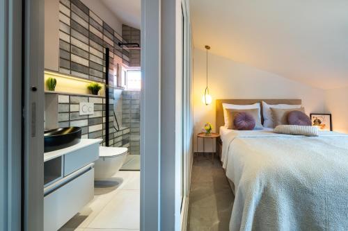 ein Schlafzimmer mit einem Bett und ein Badezimmer mit einem Waschbecken in der Unterkunft DANICA Luxury SeaSide Apartment in Šibenik