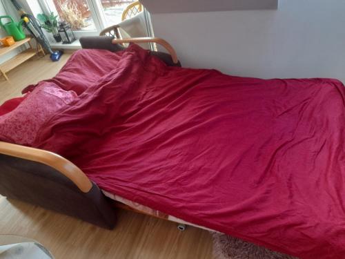 Una cama con una manta roja encima. en Jasne słoneczne mieszkanie niedaleko lotniska, en Gdansk