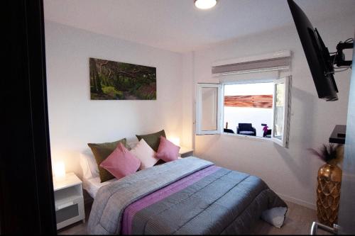 a bedroom with a bed with pink pillows and a window at Villa Nahuel in Santa Cruz de Tenerife