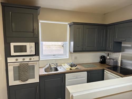 a kitchen with black cabinets and a sink and a window at Quaysiders Lakes Resort - Quaysiders Club in Ambleside