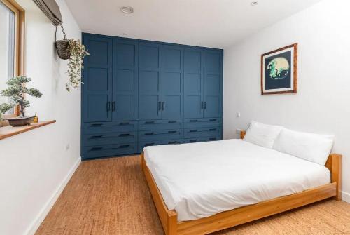 um quarto com uma cama grande e armários azuis em Modern 4 Bed Bungalow - Peaceful Rural Setting Pass the Keys em Elstree