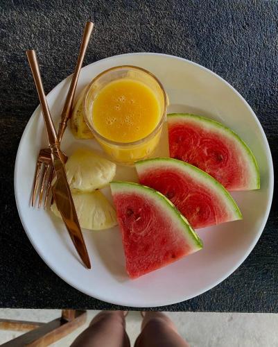 a plate of food with watermelon and a jar of juice at Jambiani Backpackers Hostel in Jambiani
