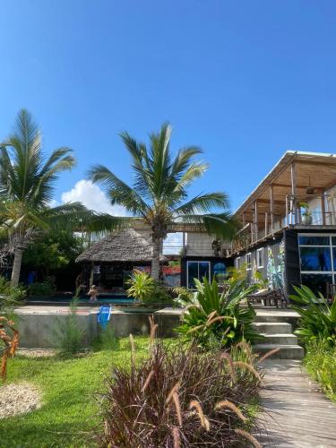 a resort with palm trees and a building at Jambiani Backpackers Hostel in Jambiani