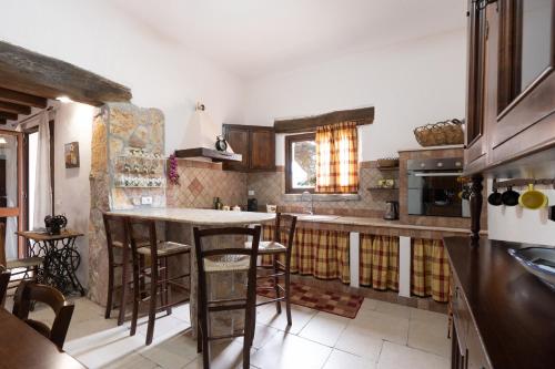 a kitchen with a counter and a bar with stools at Villa Siciliana con piscina privata in Buseto Palizzolo