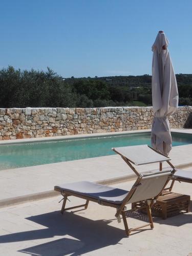 a chair and an umbrella next to a swimming pool at Antica Masseria San Benedetto in Ostuni