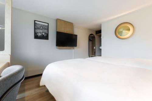 a bedroom with a white bed and a tv at Campanile Toulouse Nord l'Union in LʼUnion
