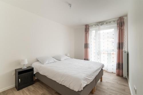 een witte slaapkamer met een bed en een raam bij Moulin à Vent Nord - Appt à 20 minutes de Paris in Bondy